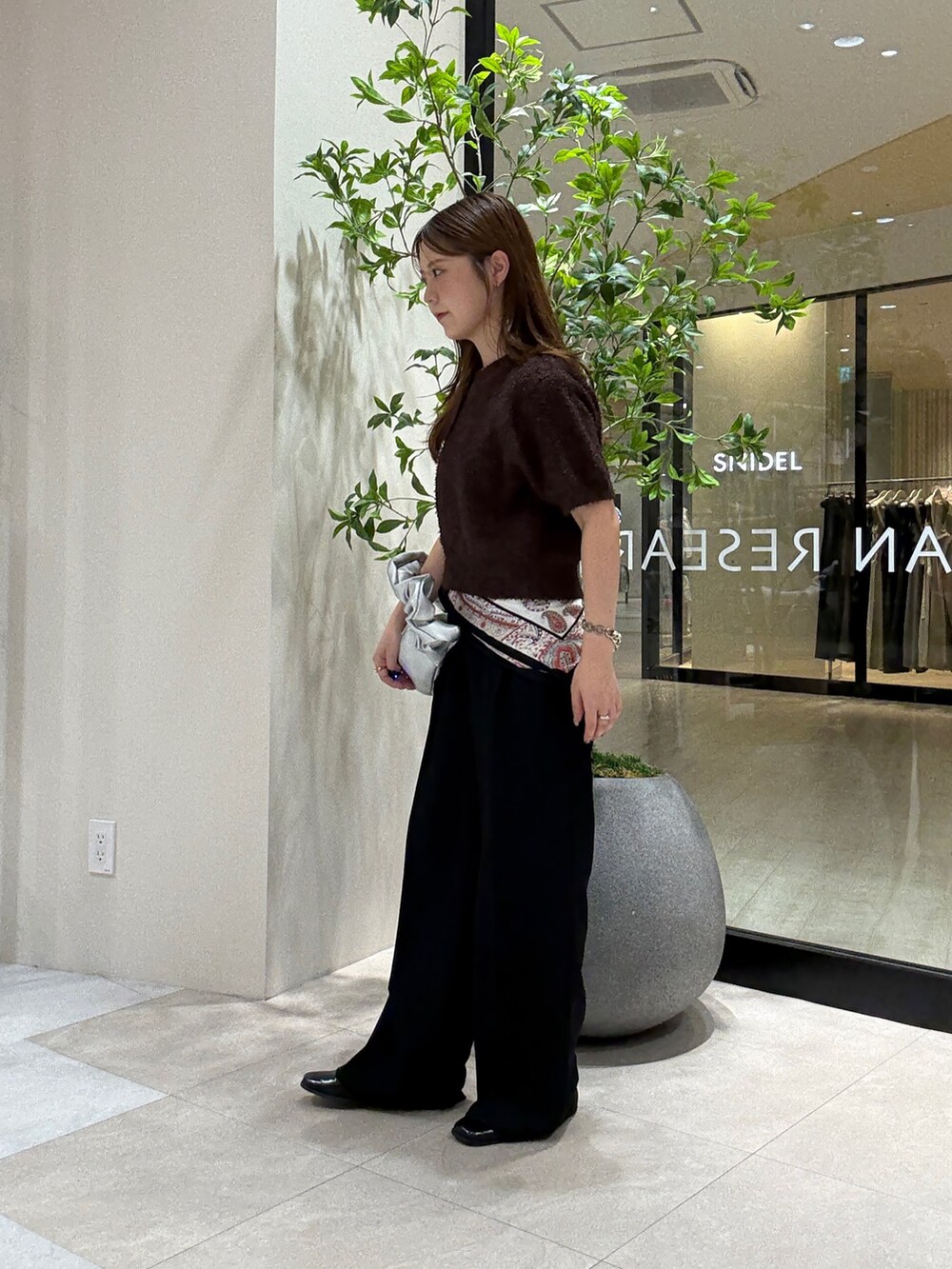 ブラウン系のニット/セーター、ブラック系のスラックス、シルバー系のハンドバッグを着用したレディースの秋コーディネートの2枚目の写真