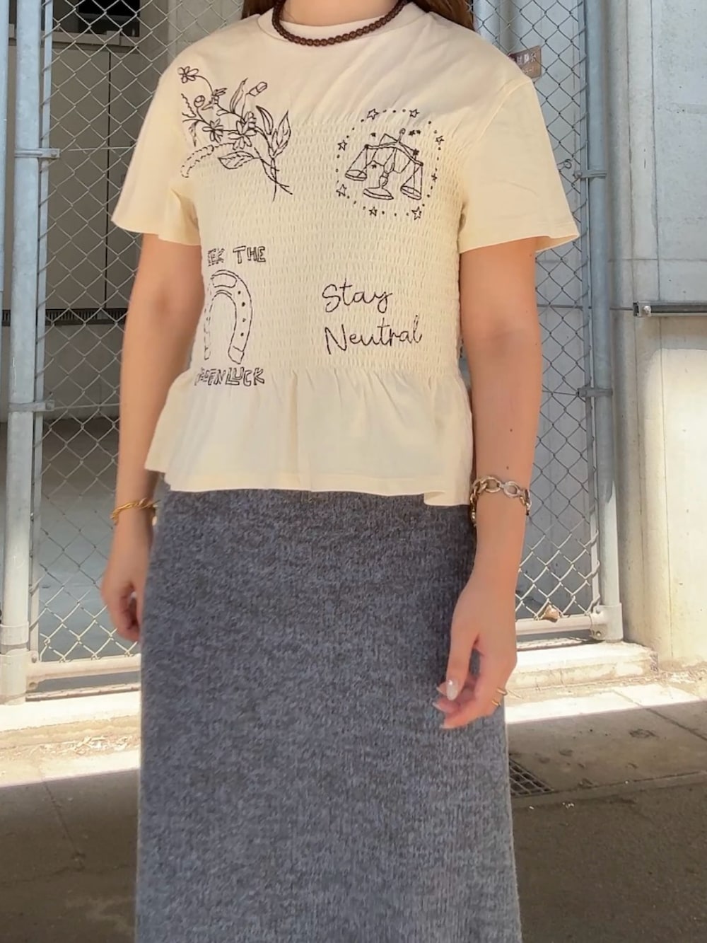 ホワイト系のTシャツ/カットソー、ブルー系のスカート、ブラウン系のネックレスを着用したレディースの夏コーディネートの4枚目の写真