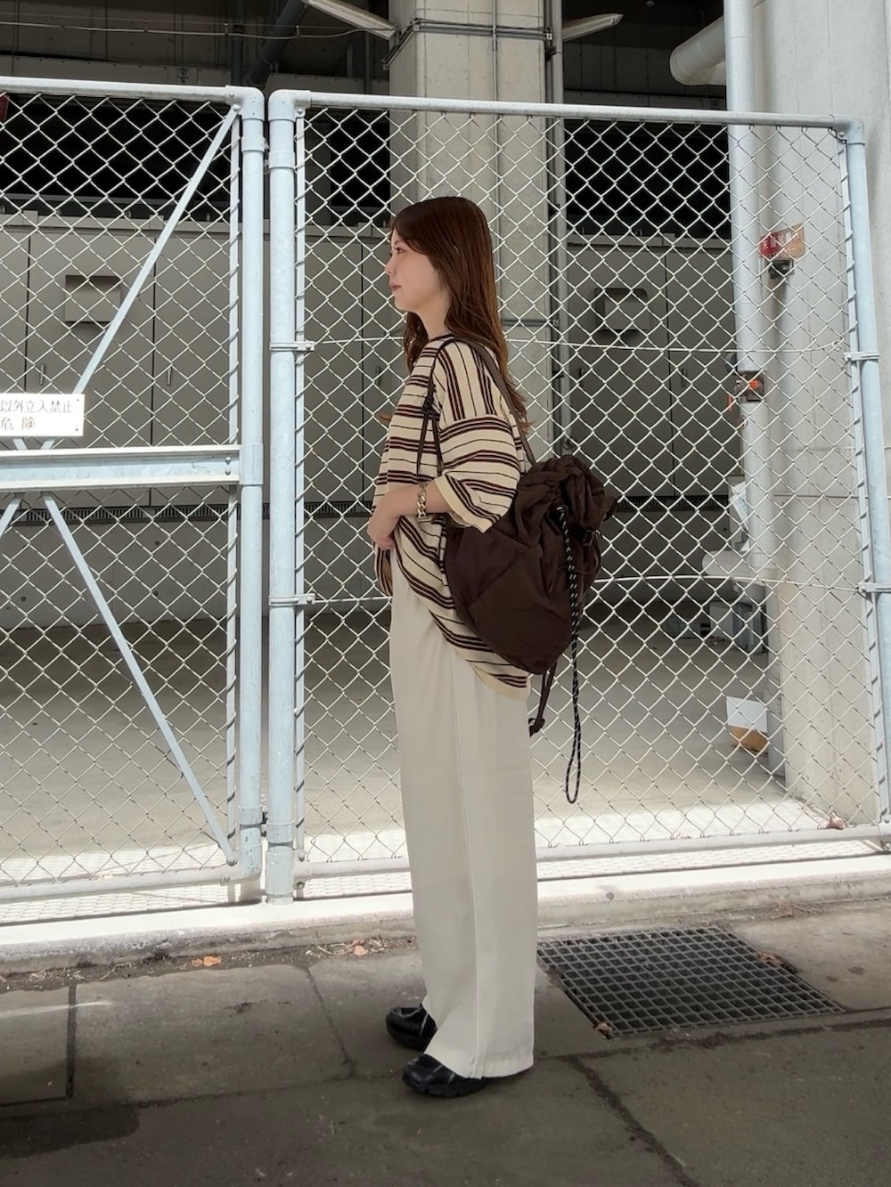 イエロー系のニット/セーター、ホワイト系のその他パンツ、ブラウン系のバックパック/リュックを着用したレディースの春コーディネートの2枚目の写真