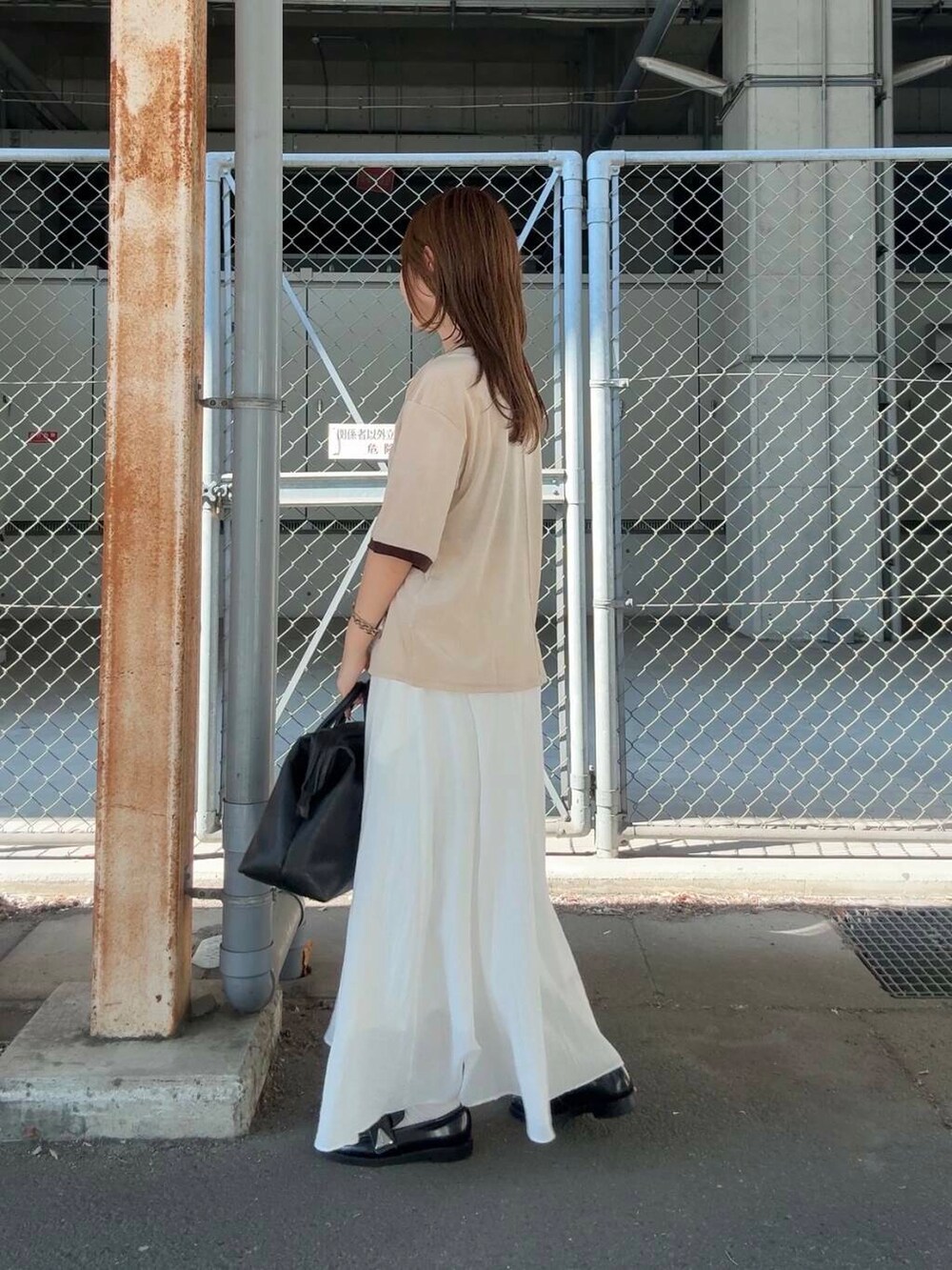 ホワイト系のスカート、ベージュ系のTシャツ/カットソー、ブラック系のボストンバッグを着用したレディースの夏コーディネートの3枚目の写真