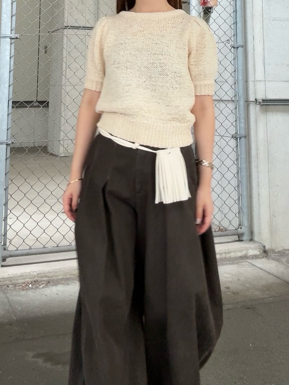 ホワイト系のニット/セーター、グレー系のその他パンツ、ホワイト系のポーチを着用したレディースの夏コーディネートの4枚目の写真