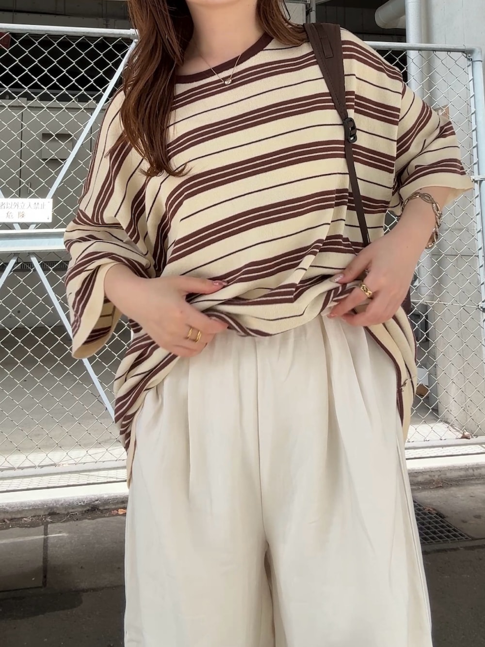 イエロー系のニット/セーター、ホワイト系のその他パンツ、ブラウン系のバックパック/リュックを着用したレディースの春コーディネートの4枚目の写真
