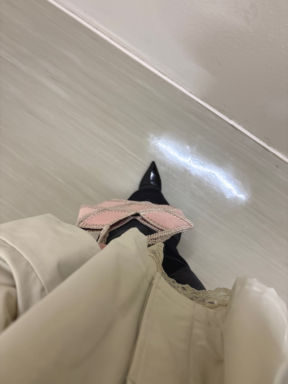 グレー系のステンカラーコート、ベージュ系のキャミソール、ブラック系のデニムパンツを着用したレディースの冬コーディネートの5枚目の写真