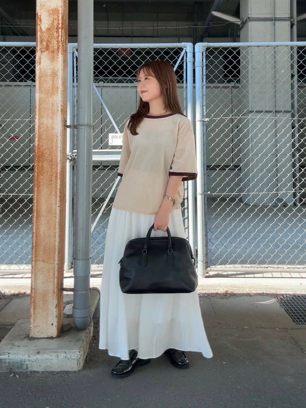 ホワイト系のスカート、ベージュ系のTシャツ/カットソー、ブラック系のボストンバッグを着用したレディースの夏コーディネートの2枚目の写真