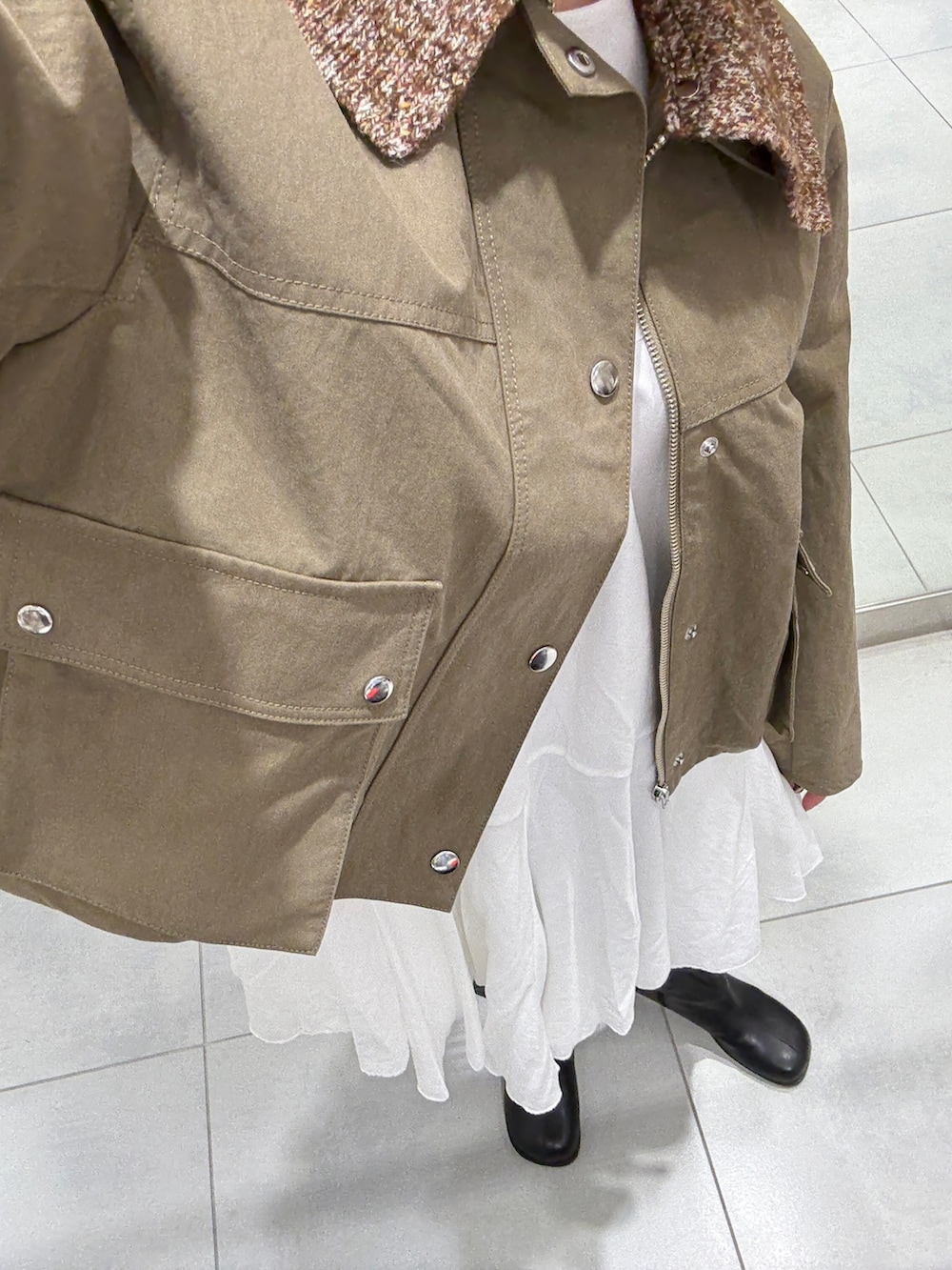 グリーン系のブルゾン、ホワイト系のワンピース、ブラック系のブーツを着用したレディースの冬コーディネートの4枚目の写真