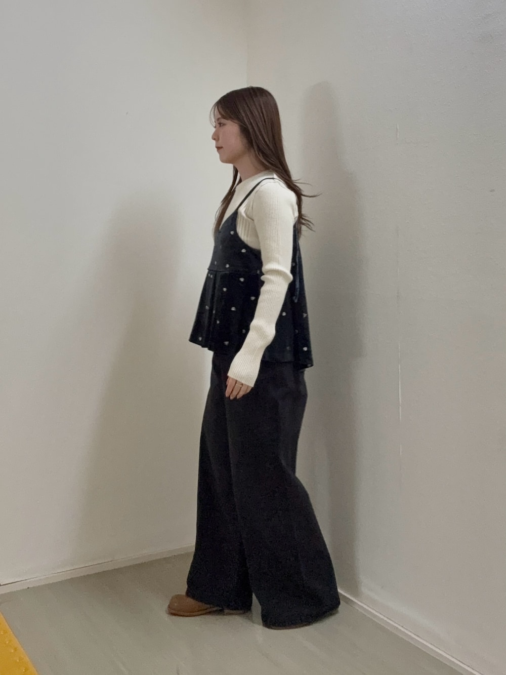 グレー系のキャミソール、ホワイト系のニット/セーター、ブラック系のデニムパンツを着用したレディースの秋コーディネートの2枚目の写真