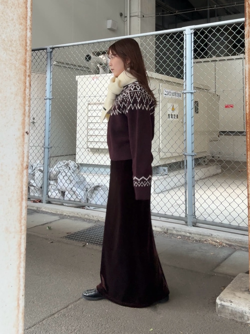 レッド系のニット/セーター、ブラウン系のスカート、ホワイト系のマフラーを着用したレディースの冬コーディネートの3枚目の写真