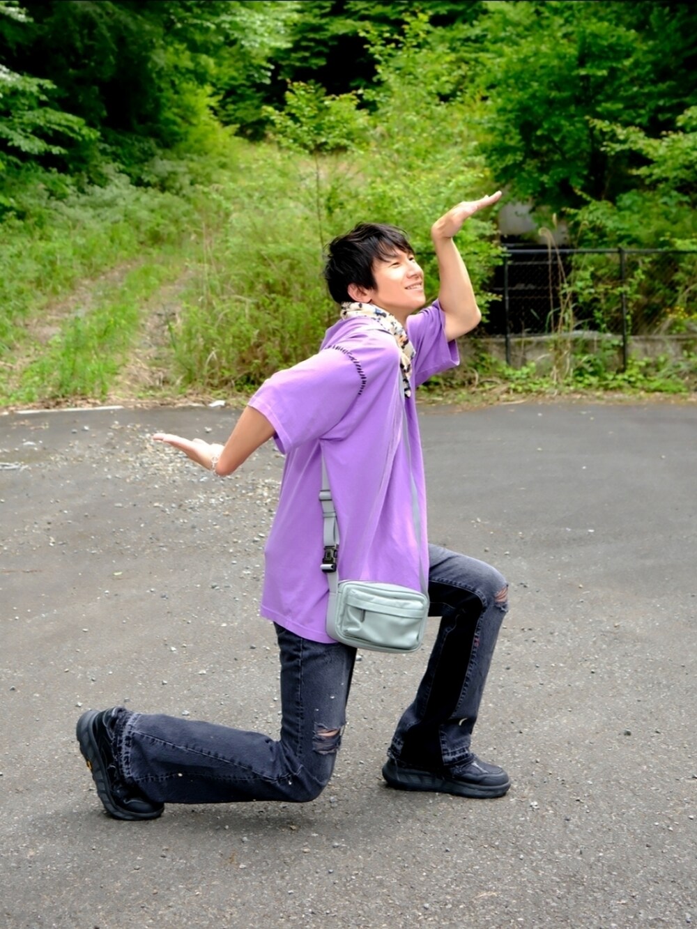 パープル系のTシャツ/カットソー、グリーン系のショルダーバッグ、ブラック系のデニムパンツを着用したメンズの春コーディネートの2枚目の写真
