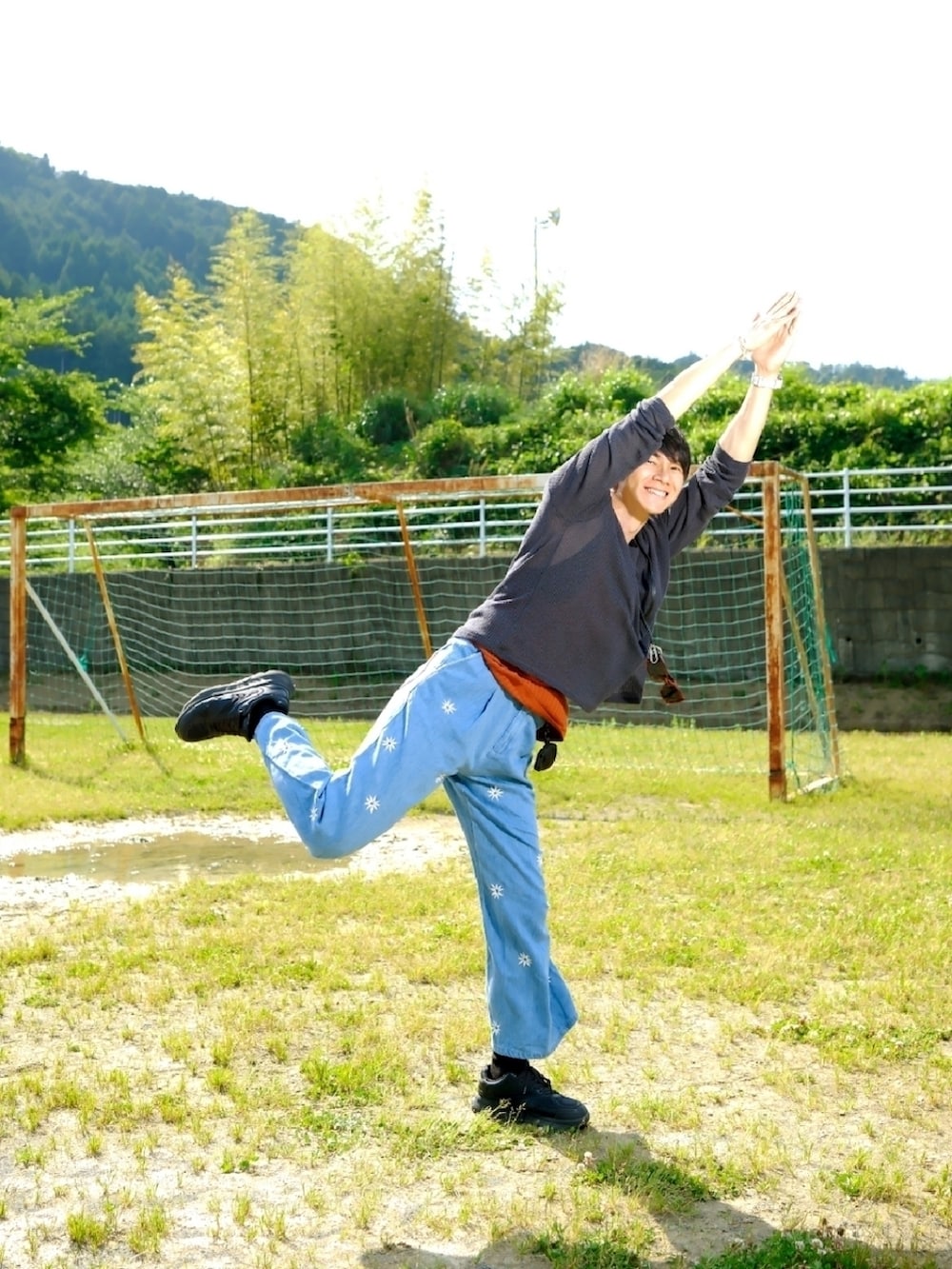 ブラック系のニット/セーター、レッド系のタンクトップ、ブルー系のデニムパンツを着用したメンズの春コーディネートの2枚目の写真