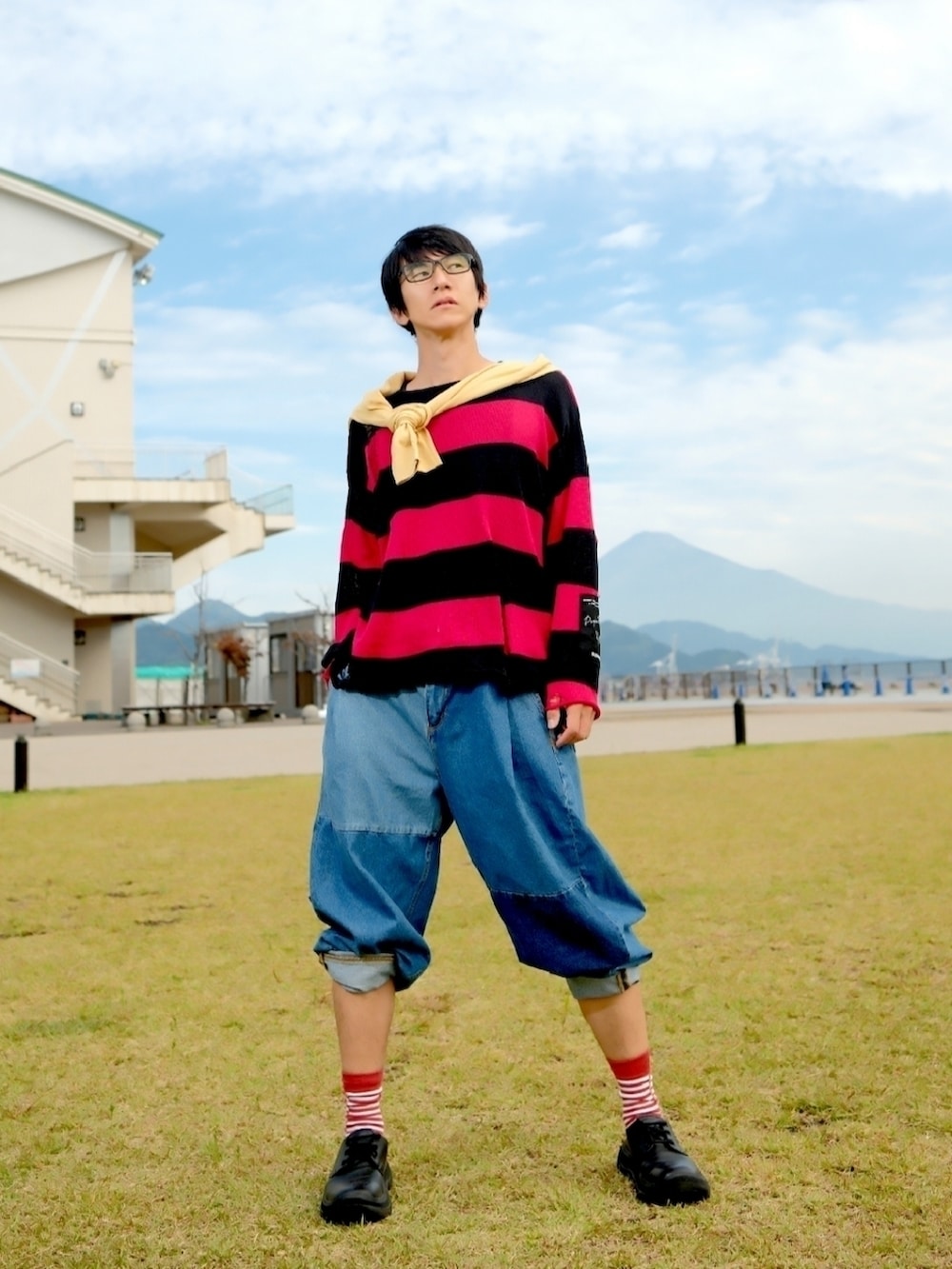 レッド系のニット/セーター、ブルー系のデニムパンツ、ブラック系のドレスシューズを着用したメンズの秋コーディネートの2枚目の写真