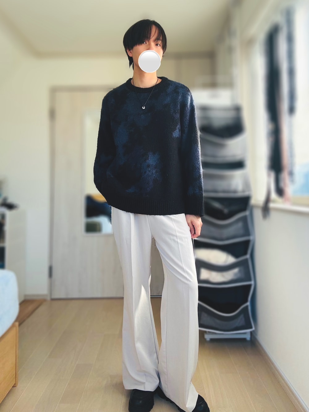 グレー系のスラックス、ブルー系のニット/セーター、ブラック系のドレスシューズを着用したメンズの冬コーディネートの2枚目の写真