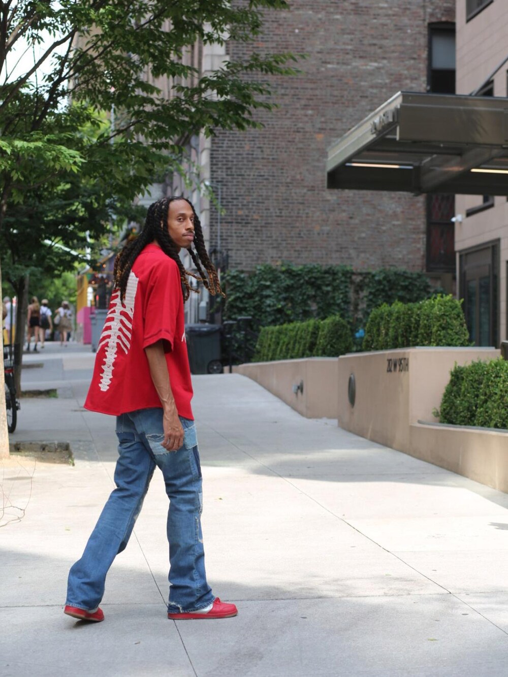 レッド系のジャージ、ブルー系のデニムパンツ、レッド系のスニーカーを着用したメンズの夏コーディネートの2枚目の写真