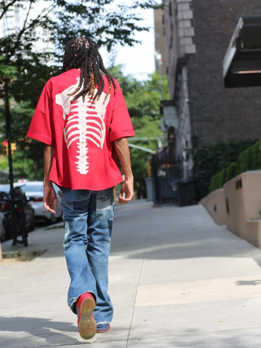 レッド系のジャージ、ブルー系のデニムパンツ、レッド系のスニーカーを着用したメンズの夏コーディネートの4枚目の写真