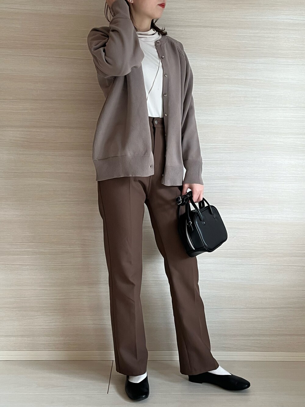 ベージュ系のカーディガン/ボレロ、ブラウン系のスラックス、ブラック系のバッグを着用したレディースの冬コーディネートの2枚目の写真