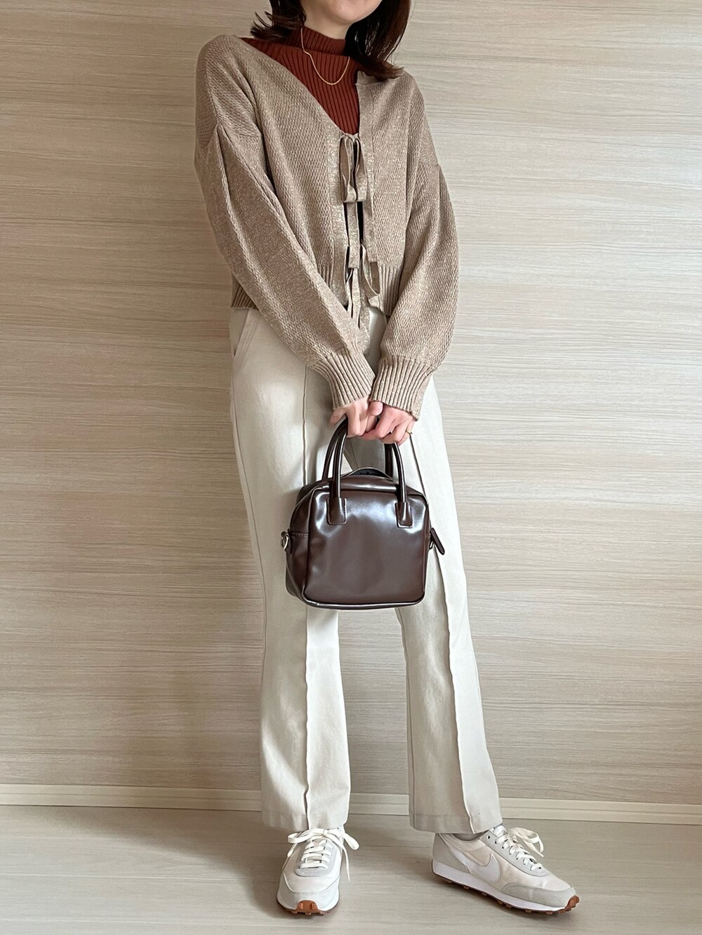 ベージュ系のカーディガン/ボレロ、オレンジ系のニット/セーター、ホワイト系のその他パンツを着用したレディースの冬コーディネートの2枚目の写真