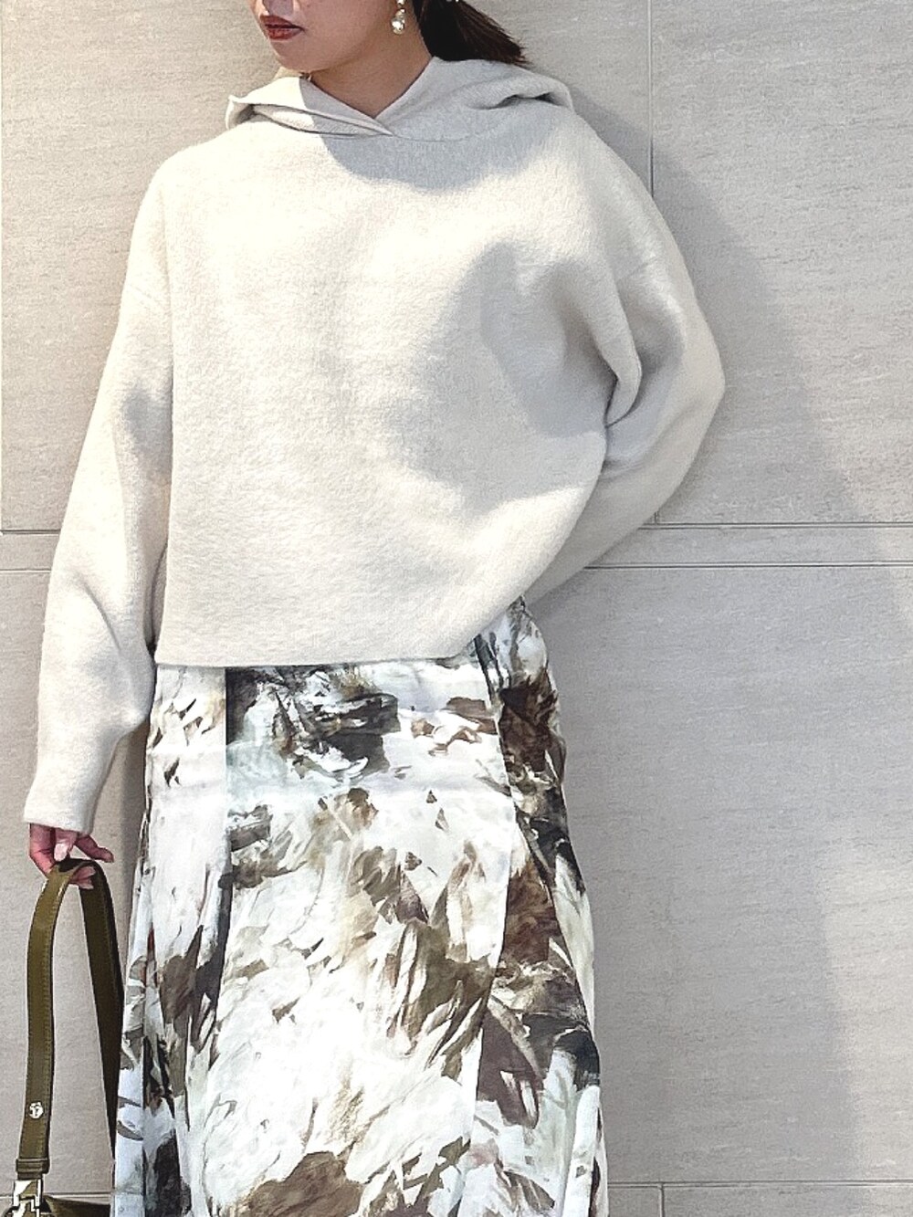 ホワイト系のパーカー、グリーン系のスカート、ブラック系のブーツを着用したレディースの秋コーディネートの6枚目の写真