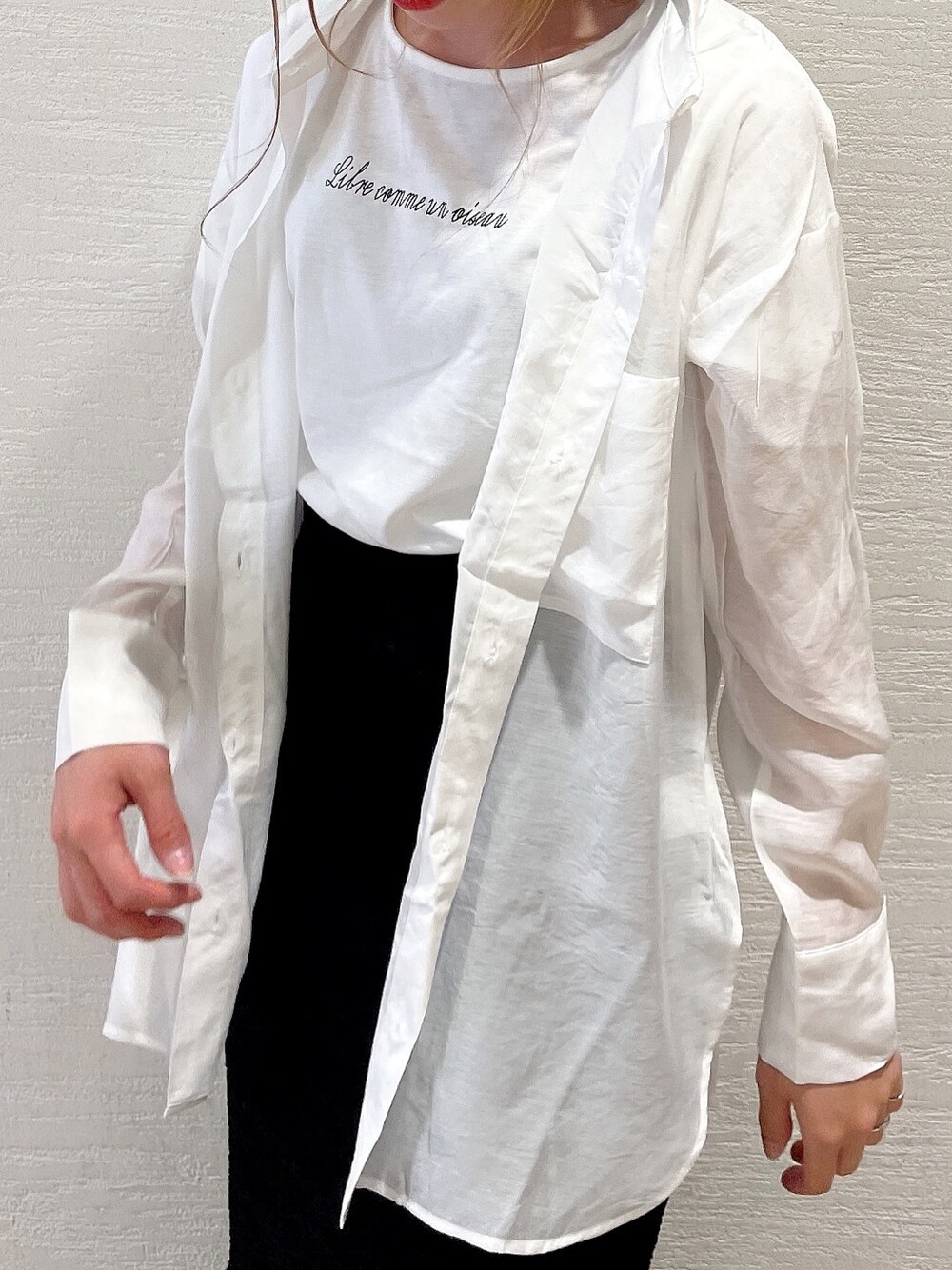 ブラック系のスカート、ホワイト系のスニーカー、ホワイト系のシャツ/ブラウスを着用したレディースの春コーディネートの2枚目の写真