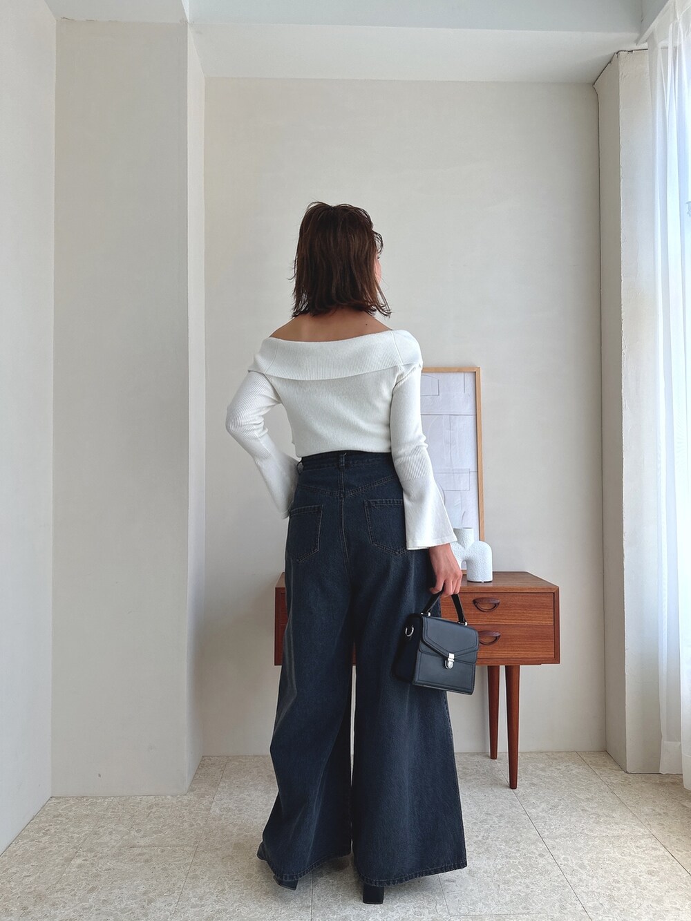 ホワイト系のニット/セーター、ブラック系のデニムパンツ、ブラック系のローファーを着用したレディースの夏コーディネートの3枚目の写真