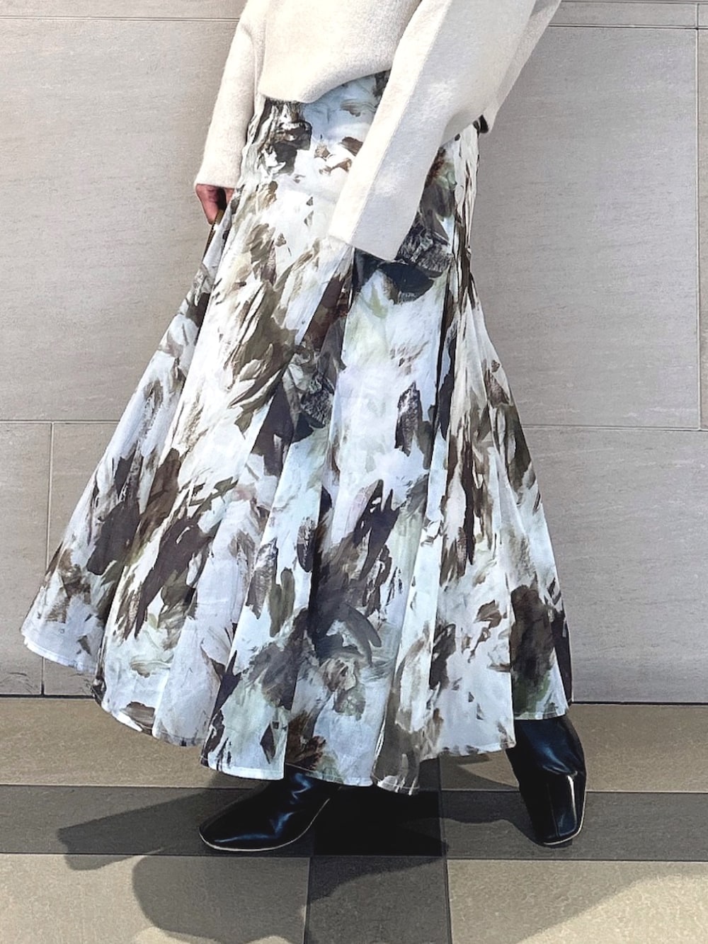 ホワイト系のパーカー、グリーン系のスカート、ブラック系のブーツを着用したレディースの秋コーディネートの4枚目の写真