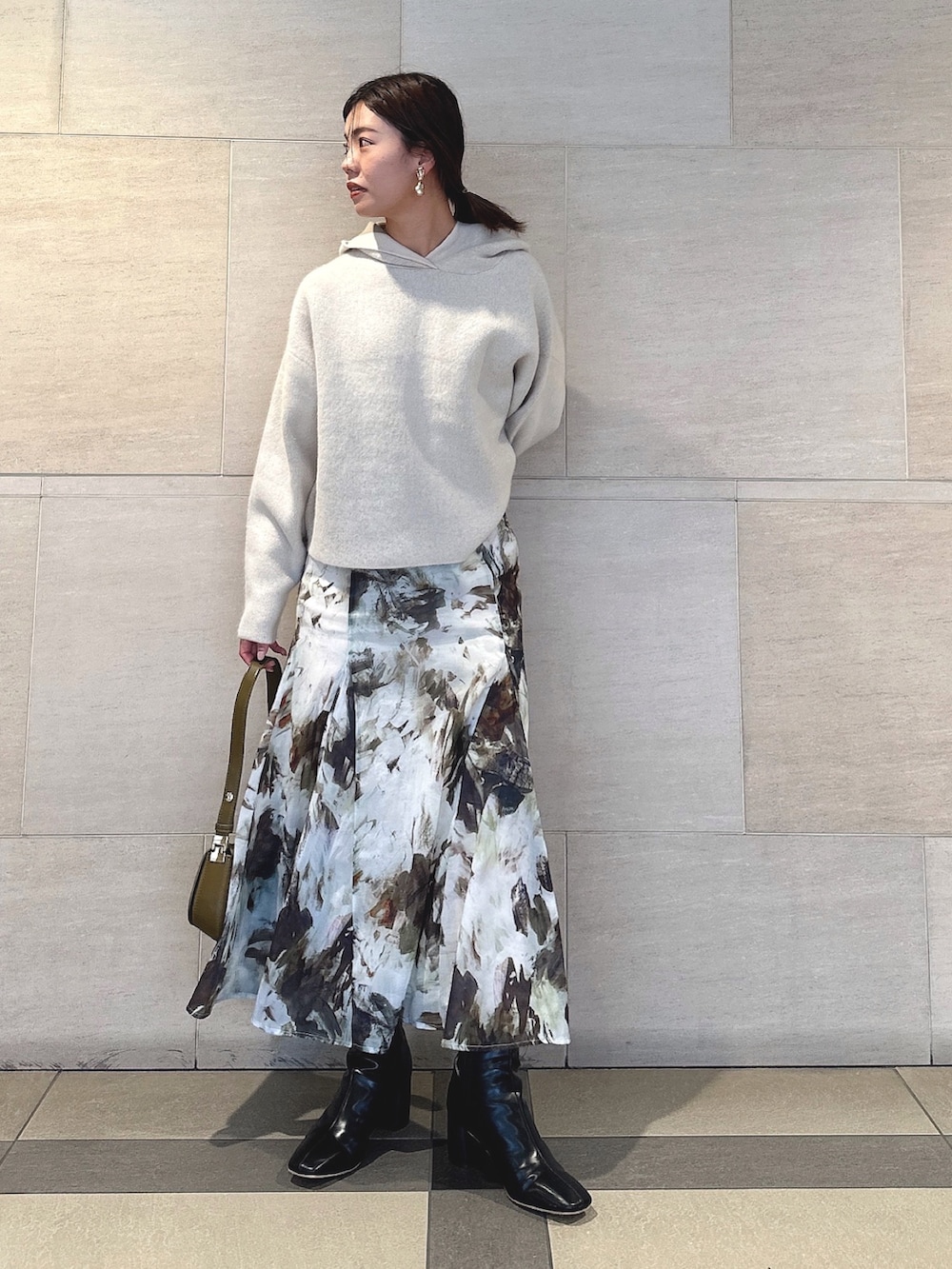 ホワイト系のパーカー、グリーン系のスカート、ブラック系のブーツを着用したレディースの秋コーディネートの5枚目の写真
