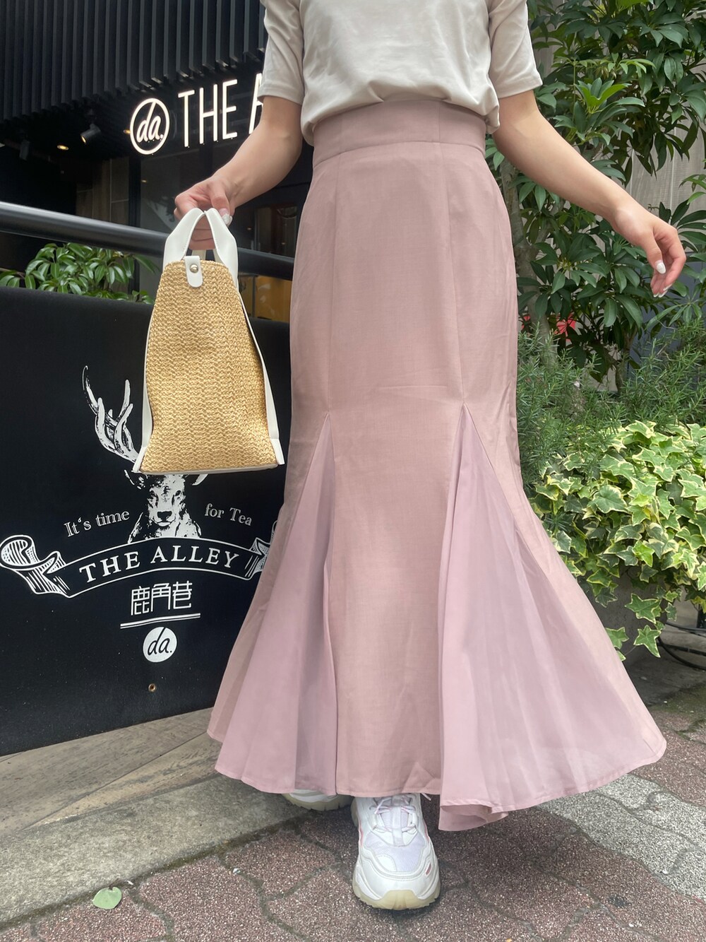 ベージュ系のTシャツ/カットソー、ピンク系のスカート、ピンク系のスニーカーを着用したレディースの春コーディネートの2枚目の写真