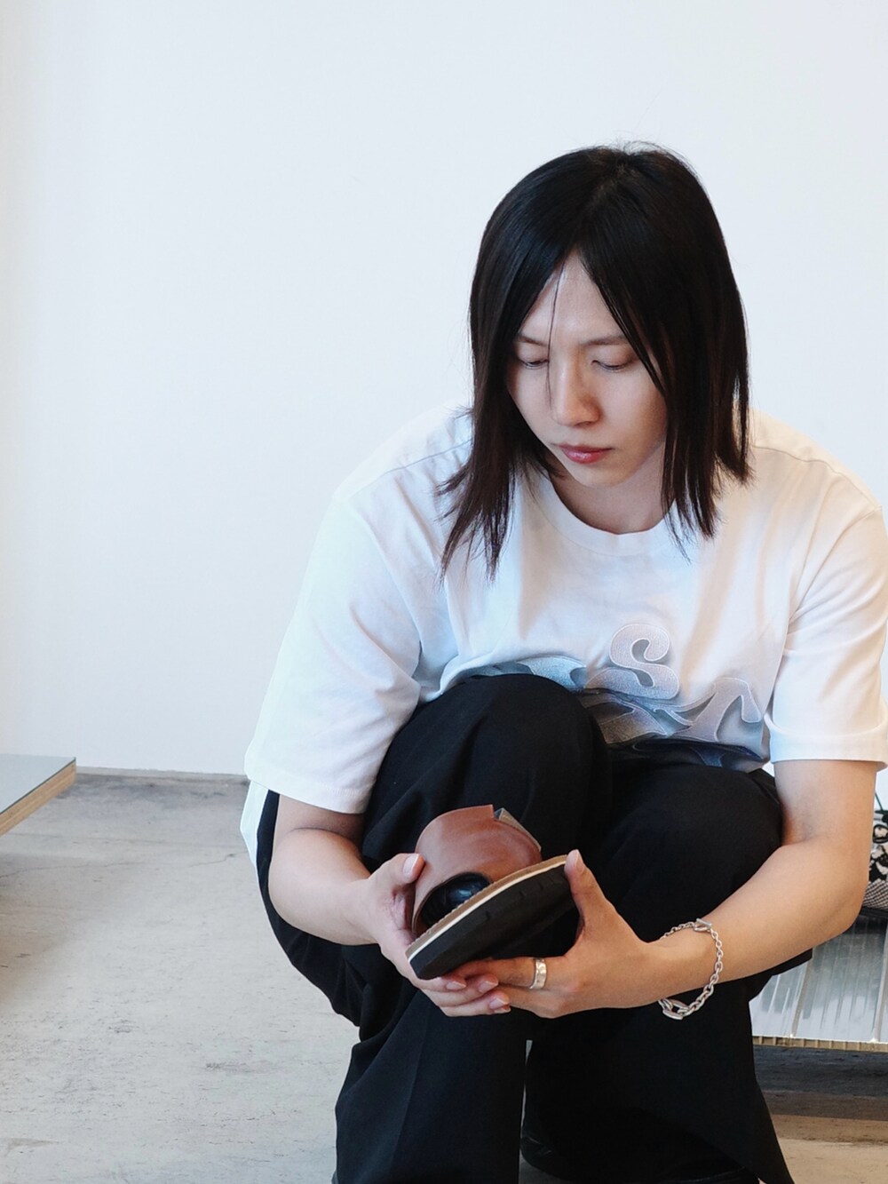 ホワイト系のTシャツ/カットソー、ブラック系のスラックス、その他のスニーカーを着用したメンズの夏コーディネートの2枚目の写真