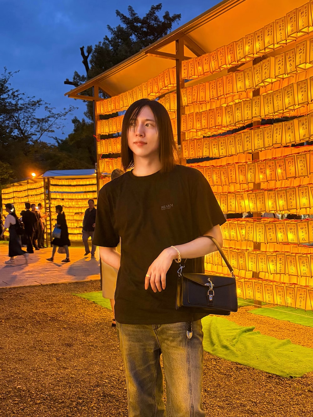 ブラック系のハンドバッグ、ブラック系のTシャツ/カットソー、ブルー系のデニムパンツを着用したメンズの夏コーディネートの3枚目の写真