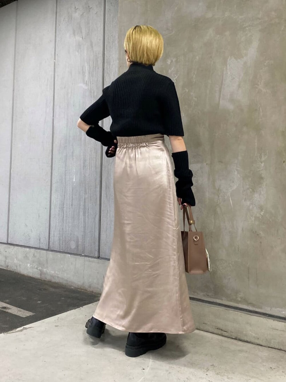 ブラック系のニット/セーター、グレー系のスカート、ブラック系のブーツを着用したレディースの秋コーディネートの3枚目の写真