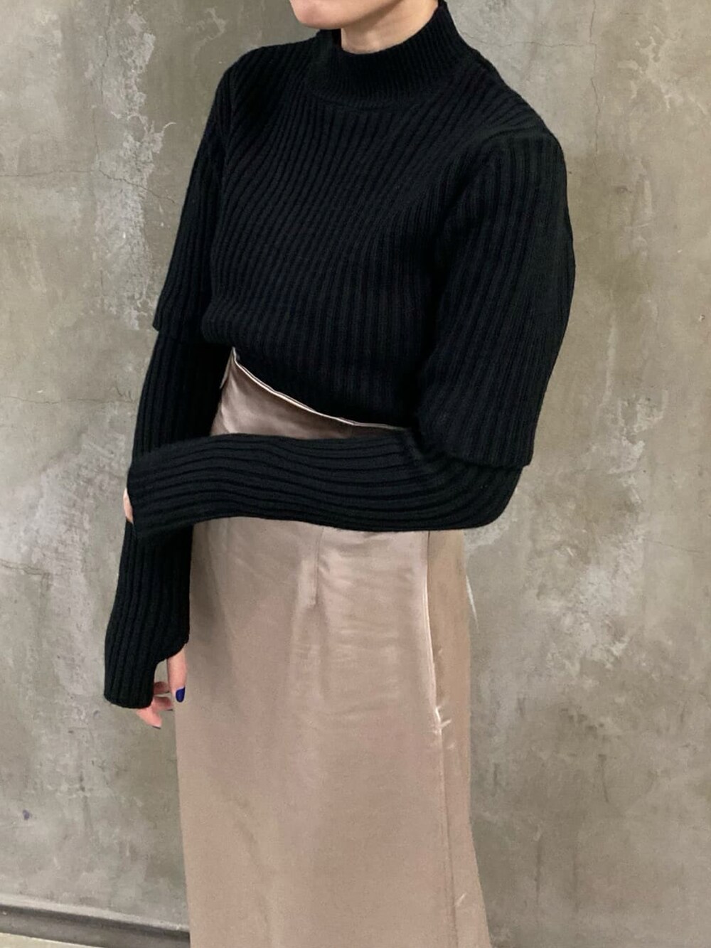 ブラック系のニット/セーター、グレー系のスカート、ブラック系のブーツを着用したレディースの秋コーディネートの5枚目の写真