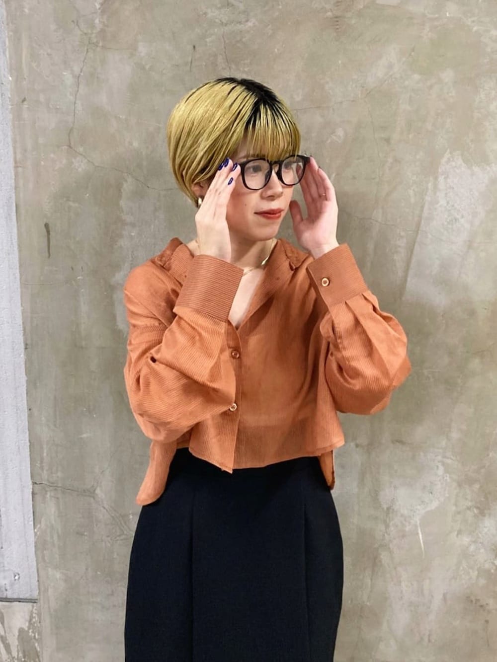 ブラック系のスカート、オレンジ系のシャツ/ブラウス、ブラック系のブーツを着用したレディースの秋コーディネートの4枚目の写真