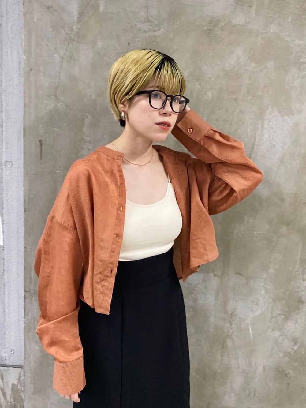 ブラック系のスカート、オレンジ系のシャツ/ブラウス、ブラック系のブーツを着用したレディースの秋コーディネートの3枚目の写真