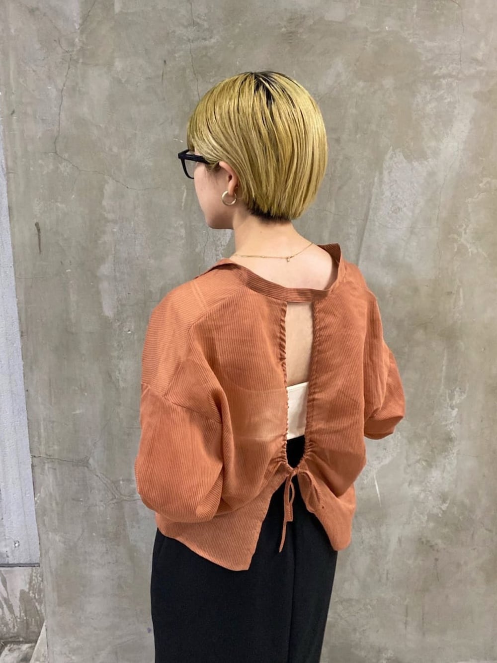 ブラック系のスカート、オレンジ系のシャツ/ブラウス、ブラック系のブーツを着用したレディースの秋コーディネートの5枚目の写真