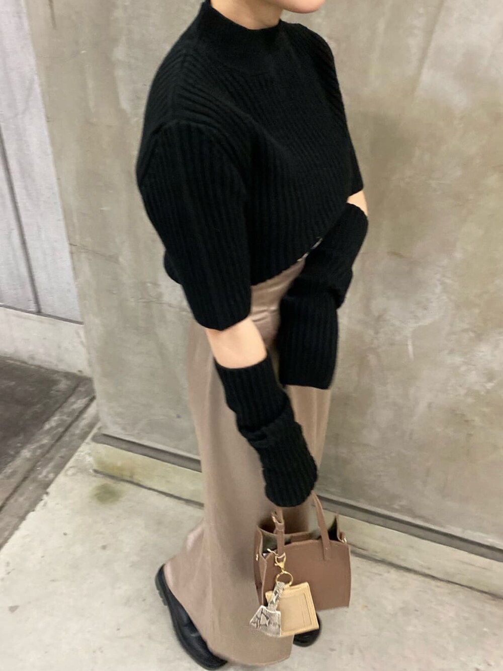 ブラック系のニット/セーター、グレー系のスカート、ブラック系のブーツを着用したレディースの秋コーディネートの4枚目の写真