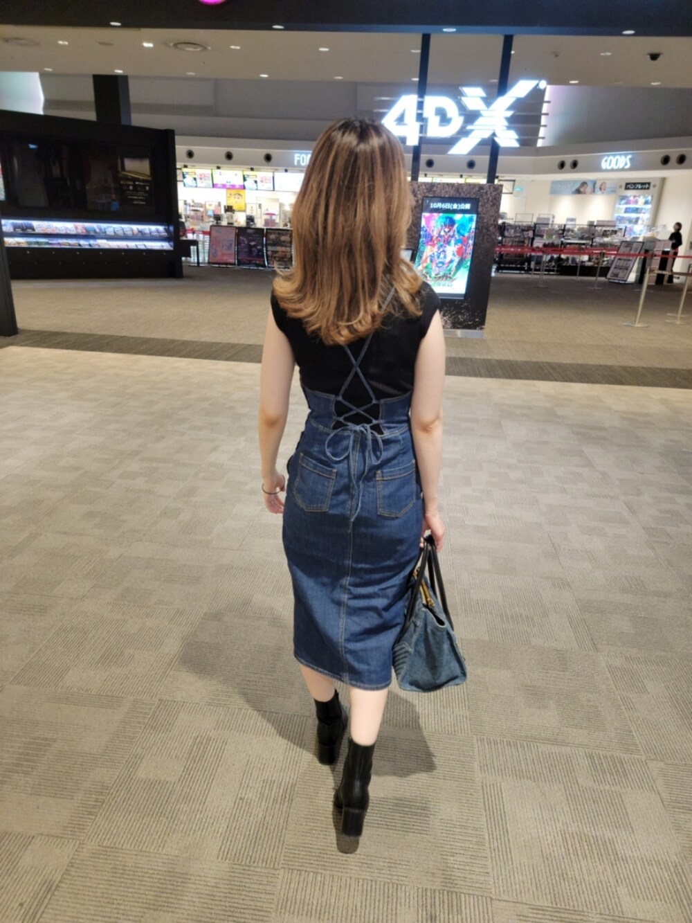 ブルー系のジャンパースカート、ブラック系のブーツ、ブルー系のショルダーバッグを着用したレディースの秋コーディネートの2枚目の写真