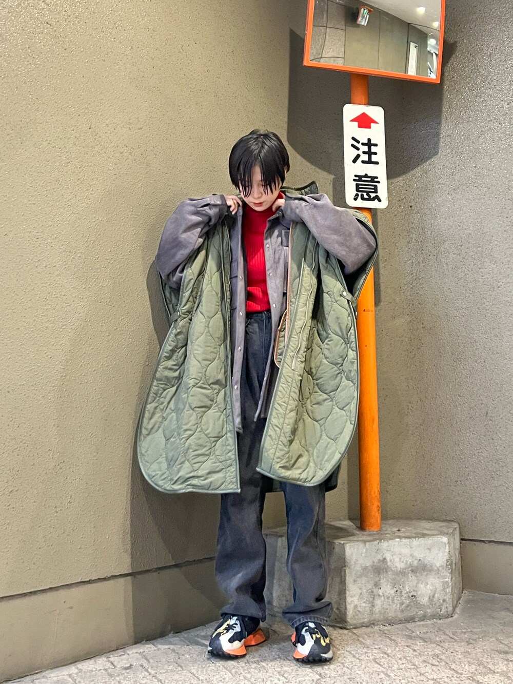 グリーン系のポンチョ、レッド系のニット/セーター、グリーン系のスニーカーを着用したレディースの秋コーディネートの3枚目の写真