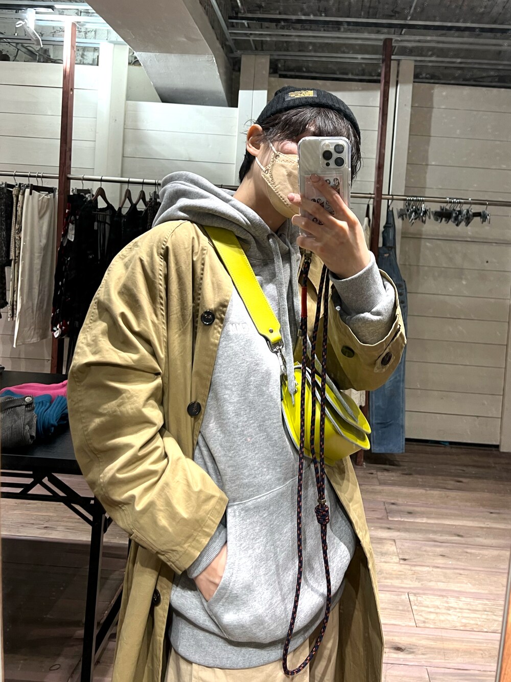 ベージュ系のトレンチコート、グレー系のパーカー、イエロー系のバッグを着用したレディースの春コーディネートの2枚目の写真