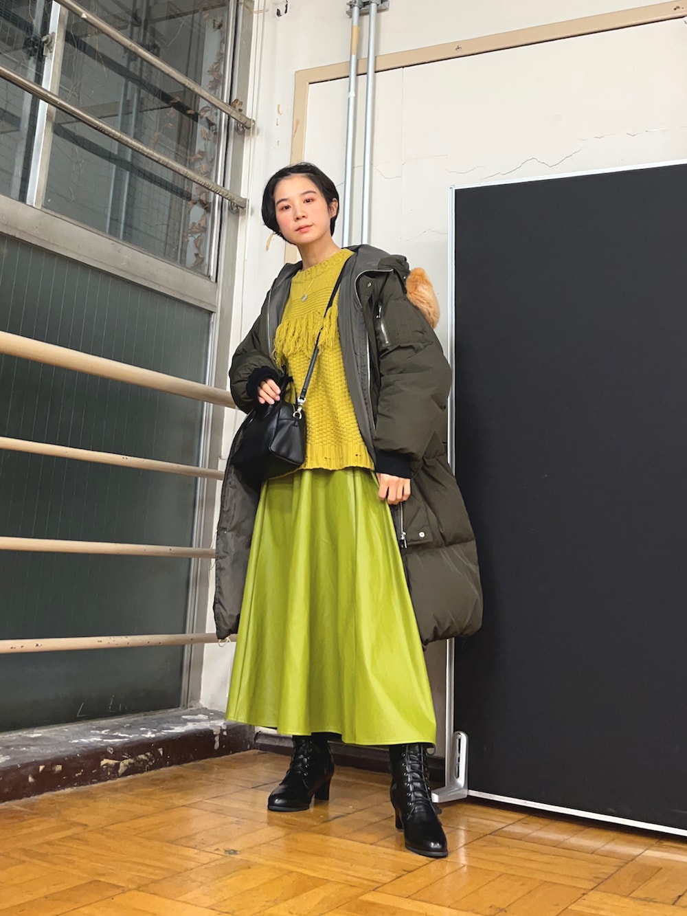 グリーン系のスカート、イエロー系のニット/セーター、ブラック系のショルダーバッグを着用したレディースの春コーディネートの2枚目の写真
