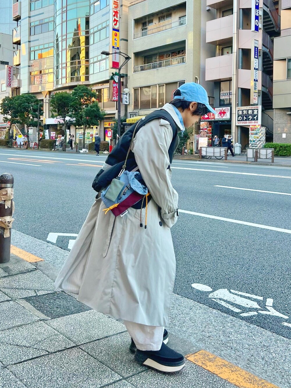 ブルー系のショルダーバッグ、ブルー系のジャケット/アウター、グレー系のトレンチコートを着用したレディースの秋コーディネートの2枚目の写真