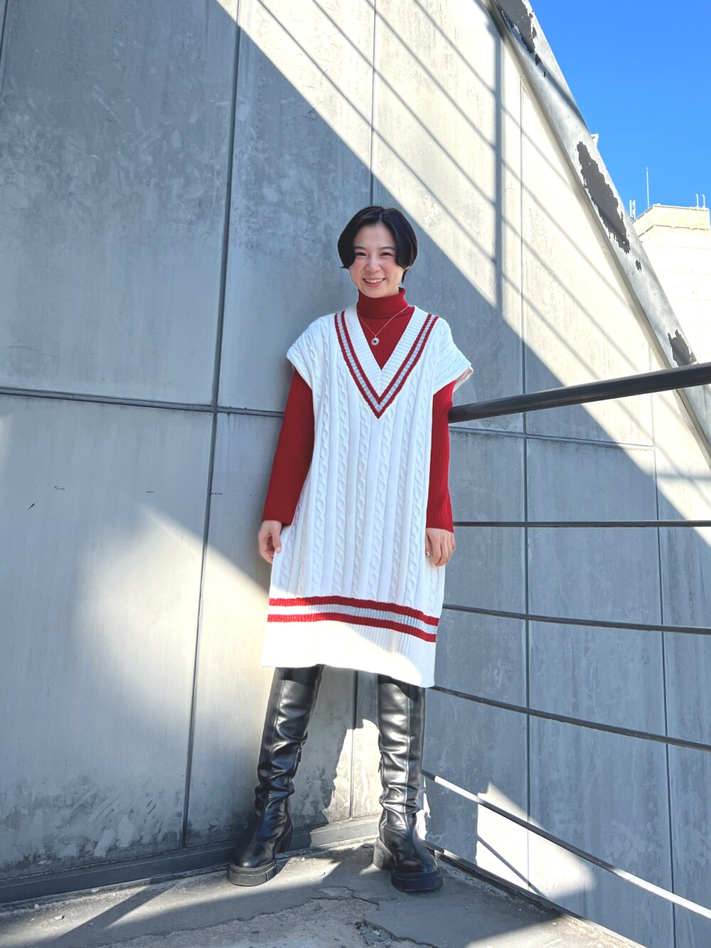 グリーン系のポンチョ、ブラック系のブーツを着用したレディースの冬コーディネートの2枚目の写真