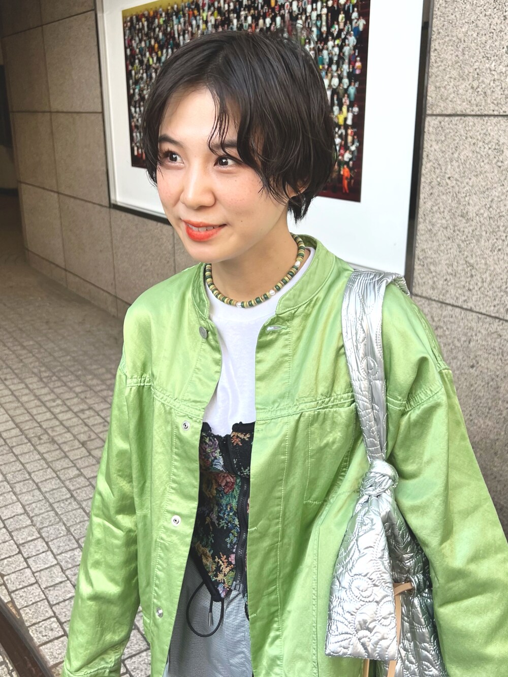 グリーン系のジャケット/アウター、グレー系のパンツ、シルバー系のショルダーバッグを着用したレディースの春コーディネートの2枚目の写真