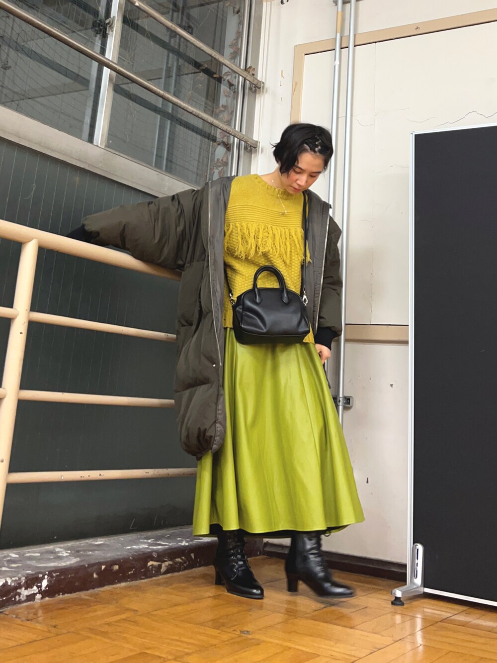 グリーン系のスカート、イエロー系のニット/セーター、ブラック系のショルダーバッグを着用したレディースの春コーディネートの3枚目の写真