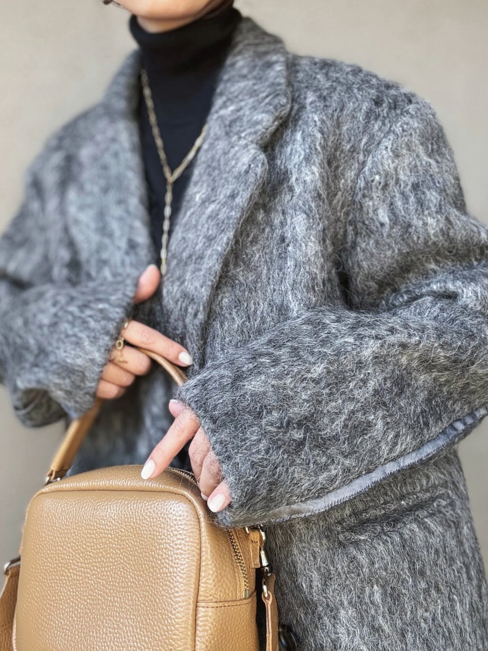 ブラック系のニット/セーター、グレー系のチェスターコート、グレー系のスカートを着用したレディースの冬コーディネートの3枚目の写真