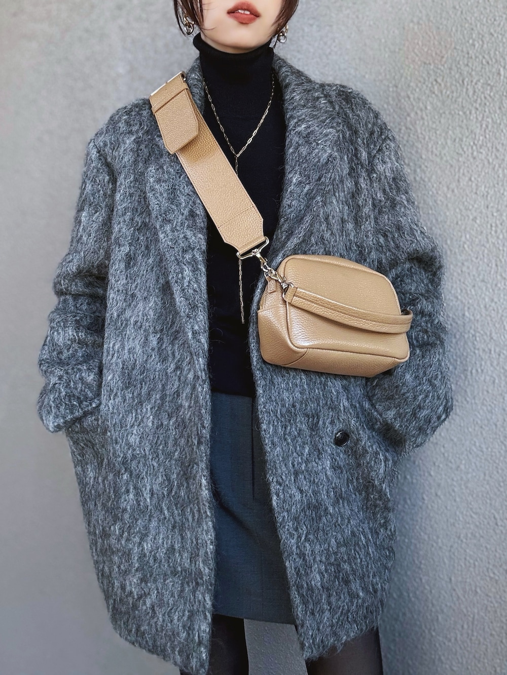 ブラック系のニット/セーター、グレー系のチェスターコート、グレー系のスカートを着用したレディースの冬コーディネートの2枚目の写真