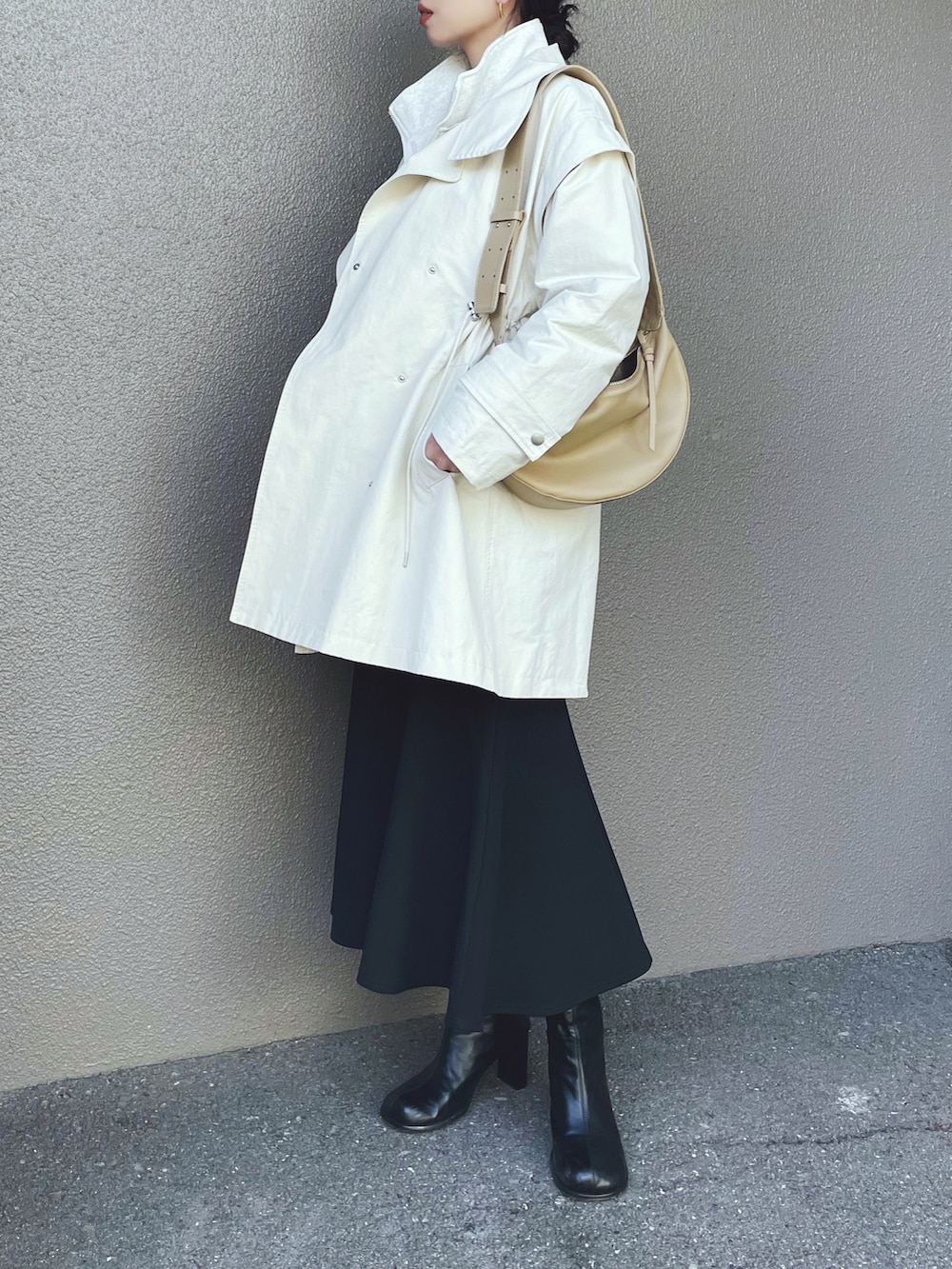 ホワイト系のトップス、ブラック系のスカート、ブラック系のブーツを着用したレディースの冬コーディネートの3枚目の写真