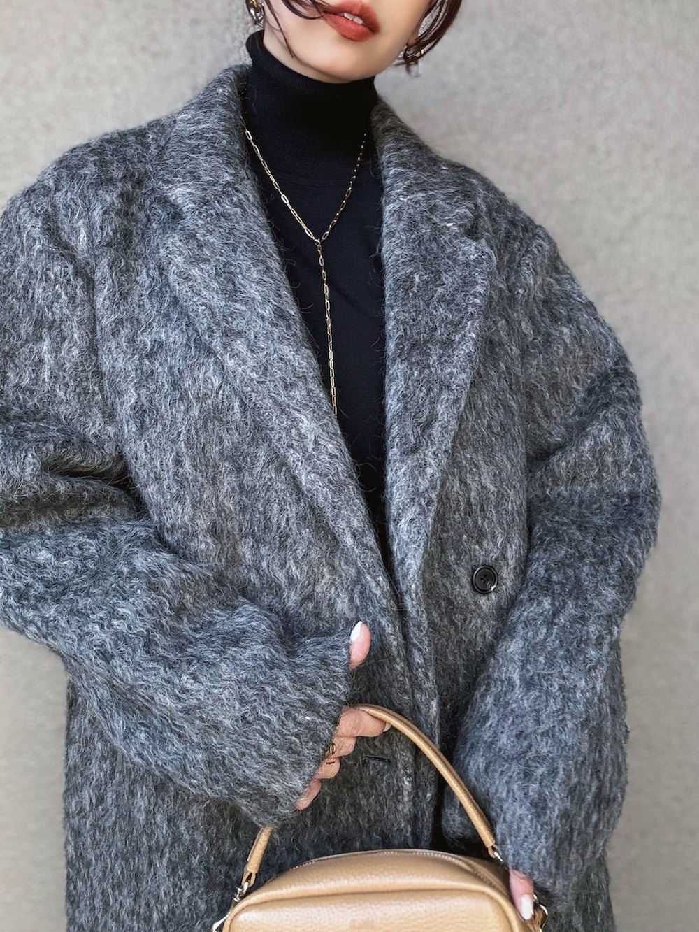 ブラック系のニット/セーター、グレー系のチェスターコート、グレー系のスカートを着用したレディースの冬コーディネートの4枚目の写真