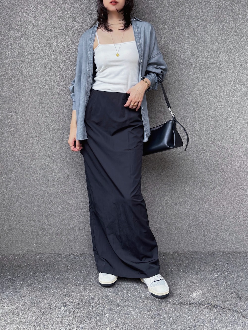 ホワイト系のキャミソール、ブラック系のスカート、ブラック系のショルダーバッグを着用したレディースの秋コーディネートの2枚目の写真