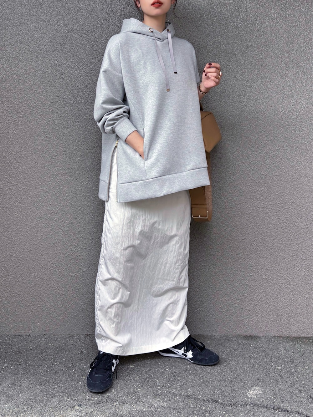 シルバー系のパーカー、ホワイト系のスカート、ブラック系のスニーカーを着用したレディースの秋コーディネートの4枚目の写真