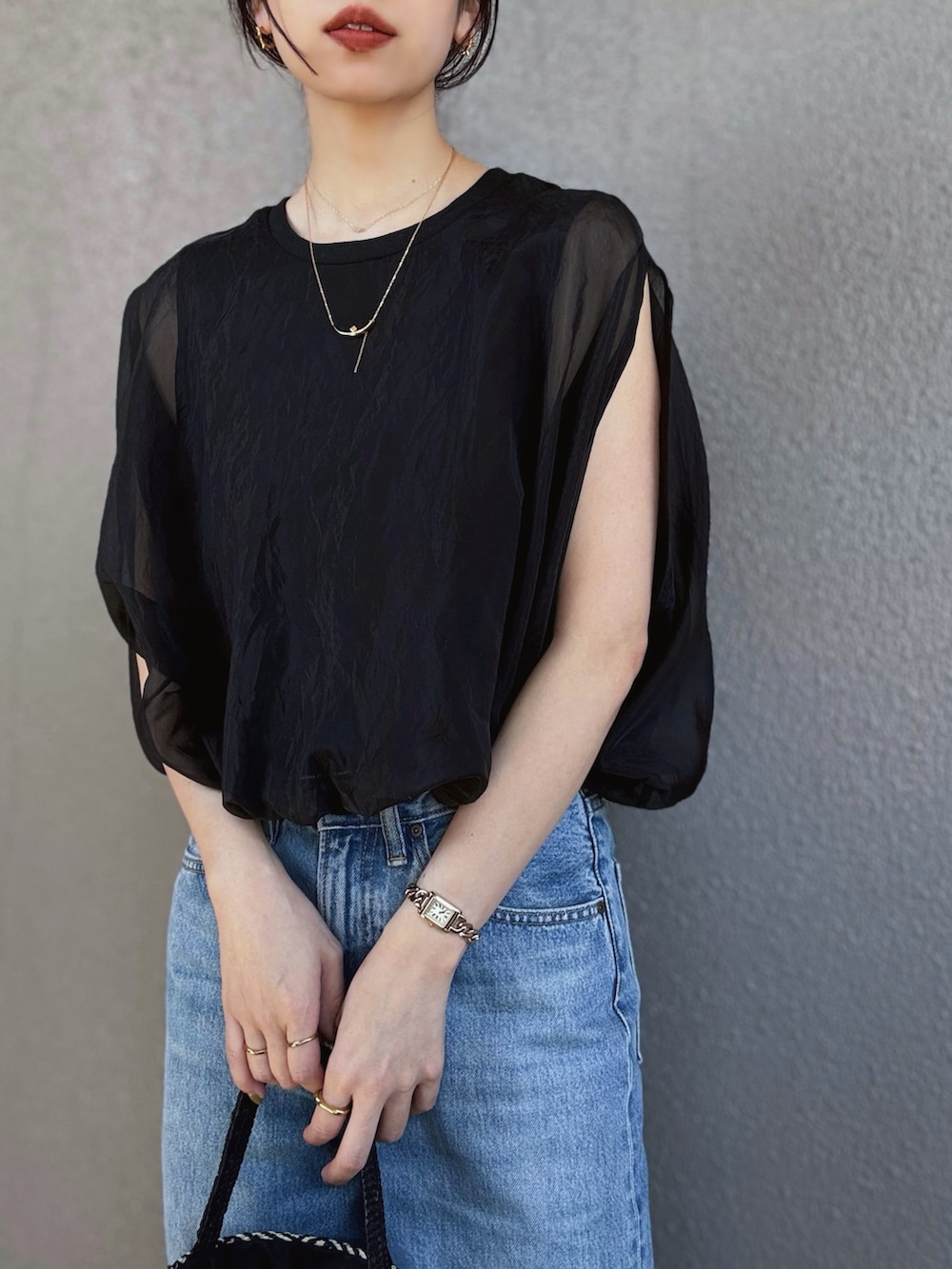 ブラック系のシャツ/ブラウス、ブルー系のデニムパンツ、ゴールド系のパンプスを着用したレディースの春コーディネートの2枚目の写真