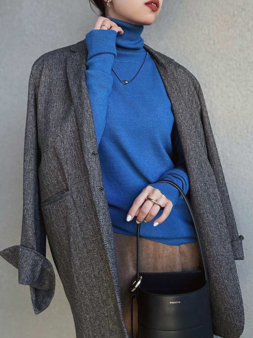 ブルー系のニット/セーター、ブラウン系のテーラードジャケット、イエロー系のスカートを着用したレディースの秋コーディネートの2枚目の写真