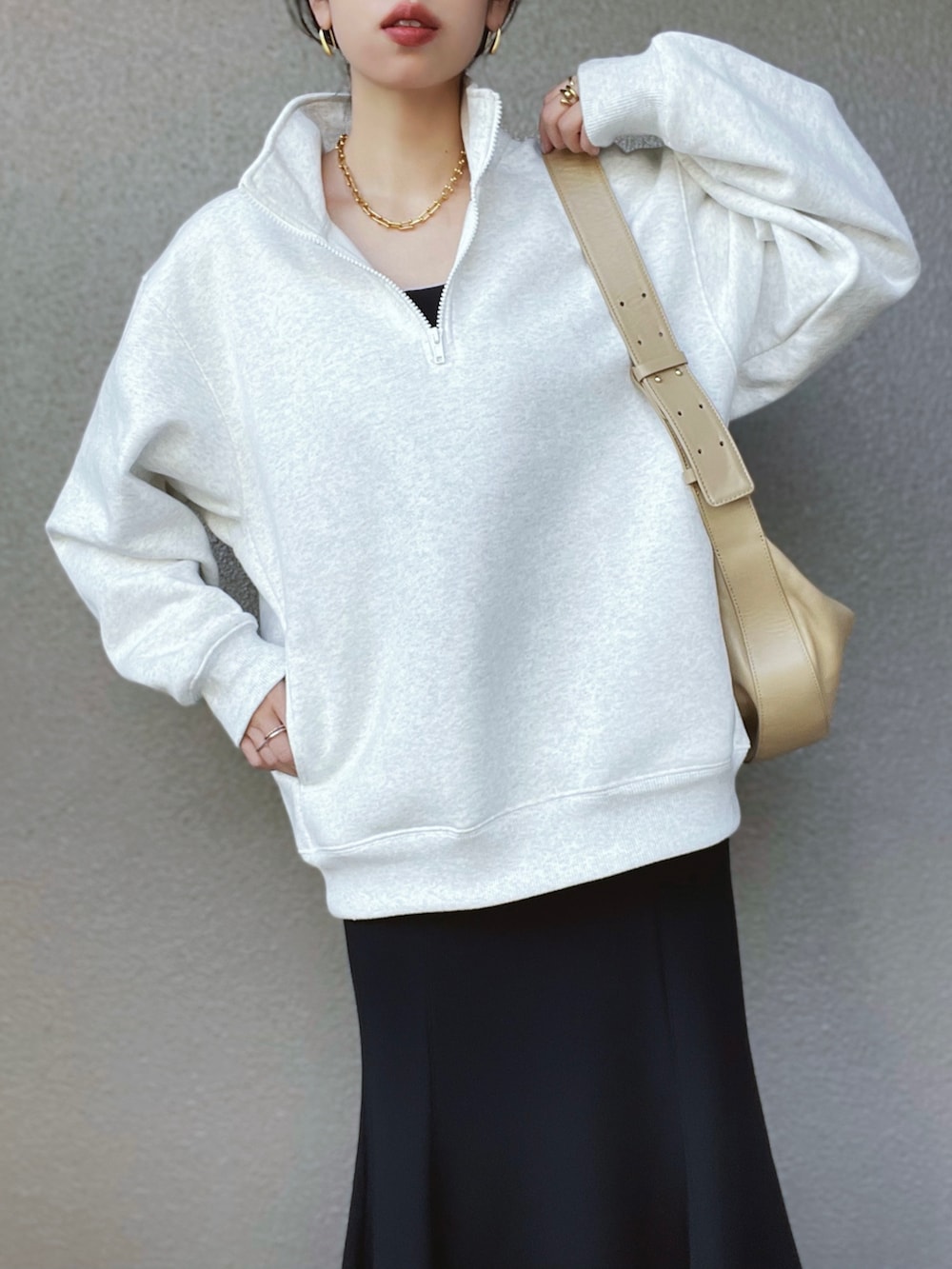 ホワイト系のトップス、ブラック系のスカート、ブラック系のブーツを着用したレディースの冬コーディネートの2枚目の写真